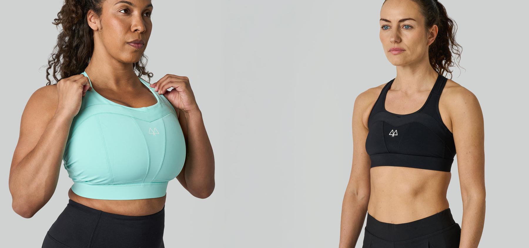 Two women wearing sports bras and black pants on a plain background