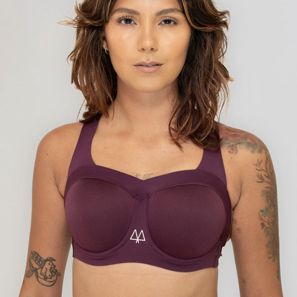 Woman wearing a maroon sports bra with a visible brand logo on a plain background