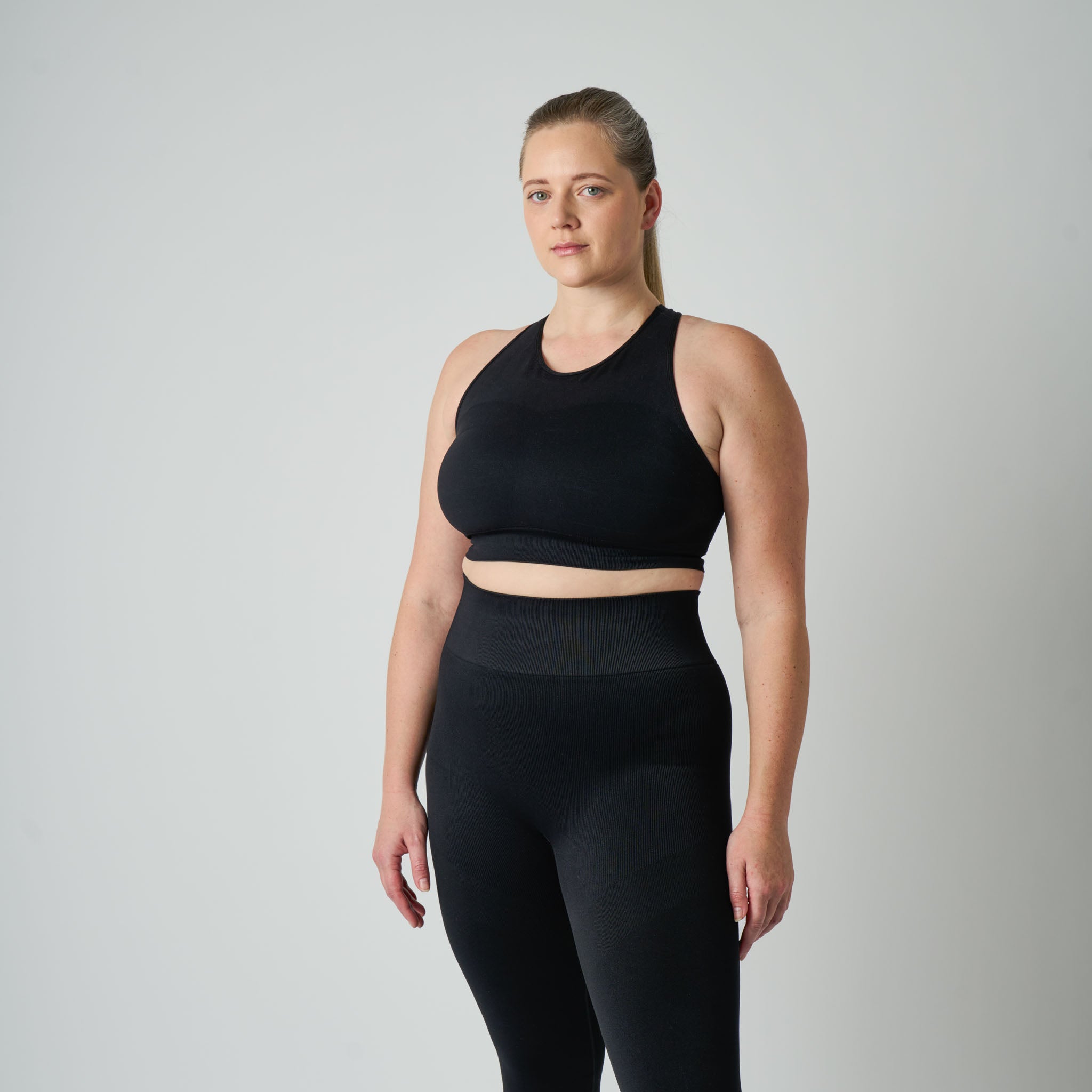 Woman wearing a black athletic outfit on a plain background