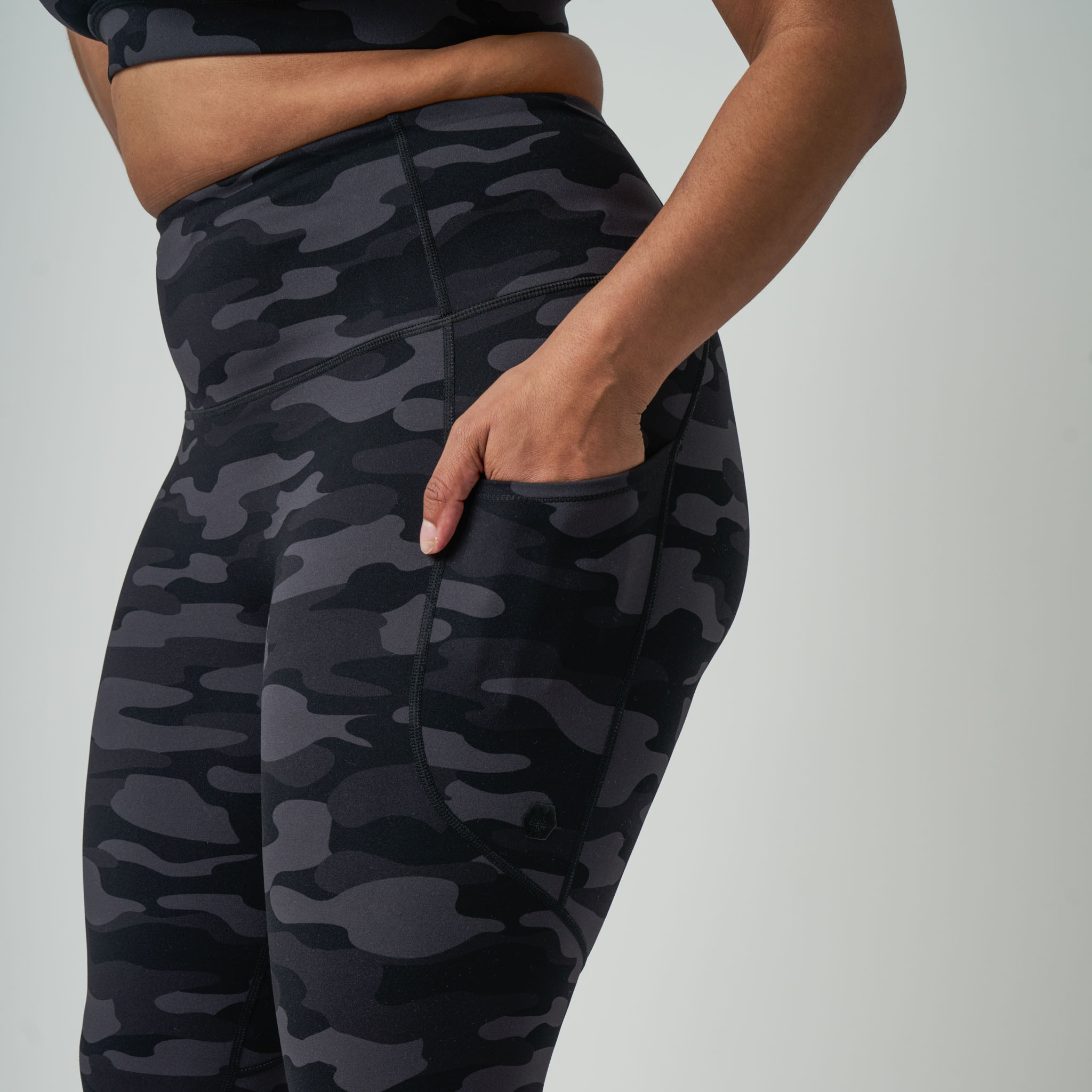 Black camouflage leggings worn by a person on a gray background