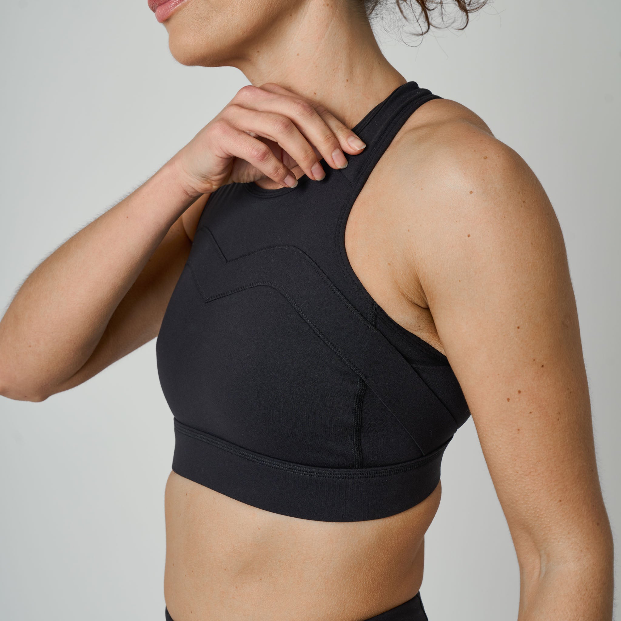 Black sports bra worn by a person on a plain background