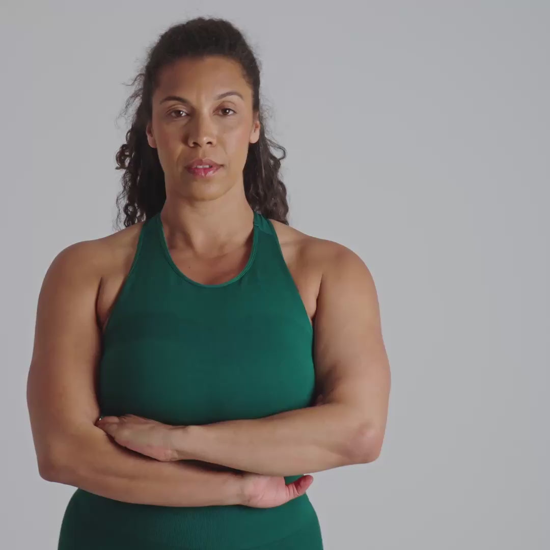 Woman wearing a green sports bra with a logo on a plain background
