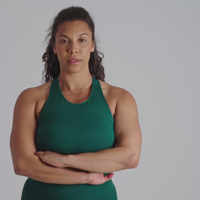 Woman wearing a green sports bra with a logo on a plain background